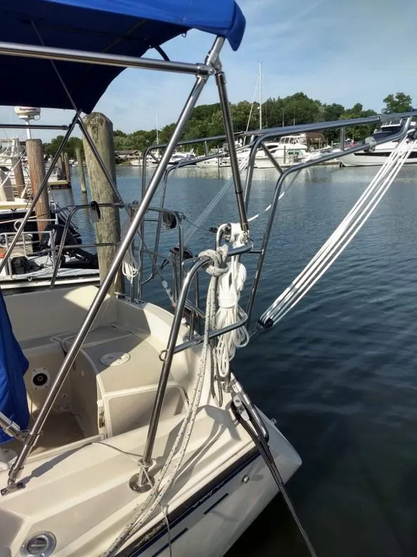 Slide: The Image of 1986 O'Day 35 sailboat docked, featuring blue canopy and rigging, in a serene marina setting. - 2