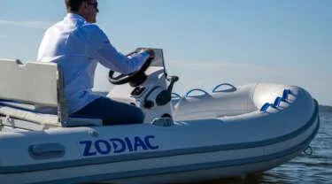 Slide: The Image of Man driving a 2024 Zodiac Nomad RIB ALU 3.6 NEO inflatable boat on water. - 3