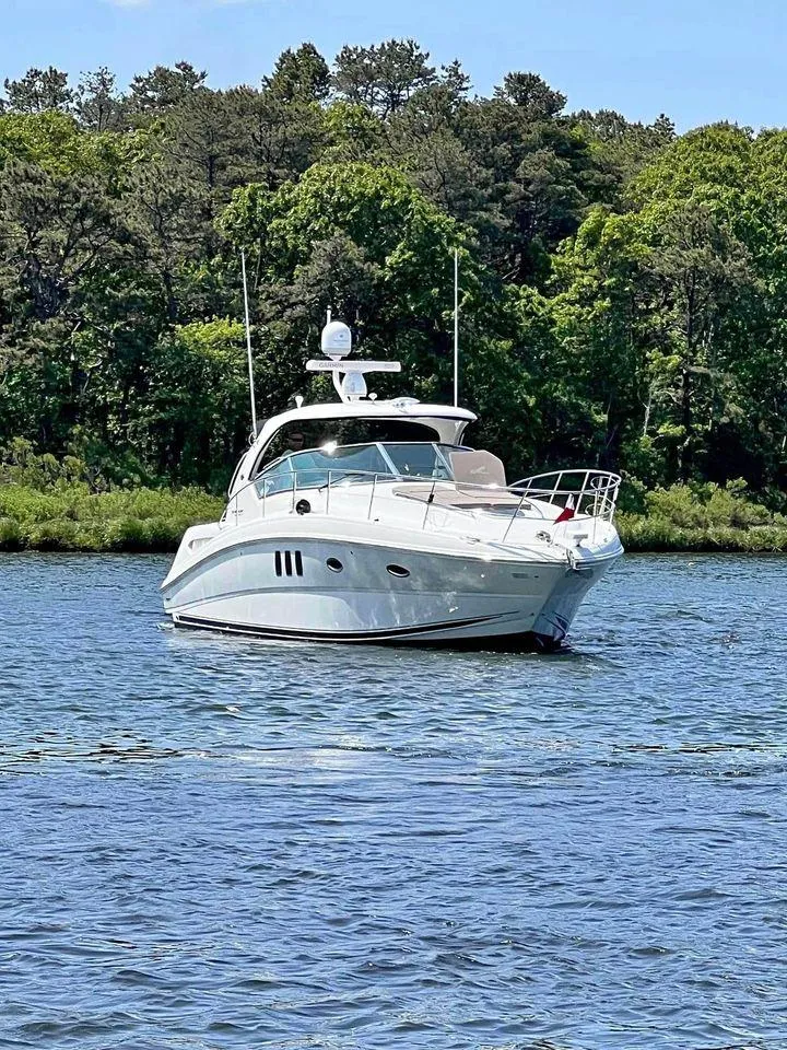Slide: The Image of 2010 Sea Ray 390 Sundancer yacht cruising on a serene lake with lush green trees. - 2