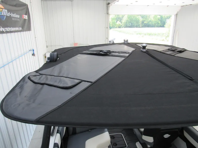 Slide: The Image of 2024 Malibu Wakesetter 23 MXZ boat with black canopy in a garage. - 20