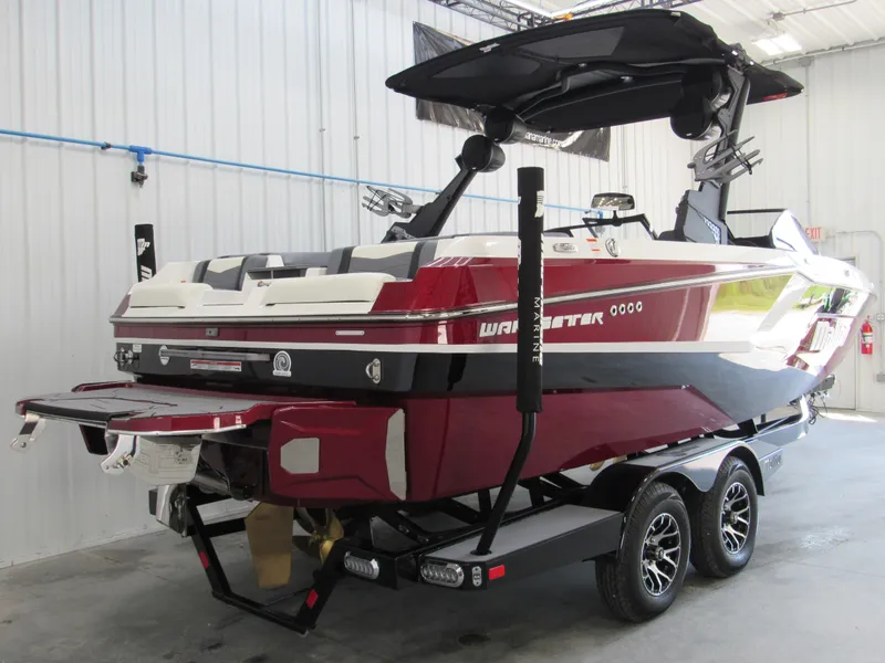 Slide: The Image of 2024 Malibu Wakesetter 23 MXZ boat in showroom, red and white exterior, on trailer. - 4
