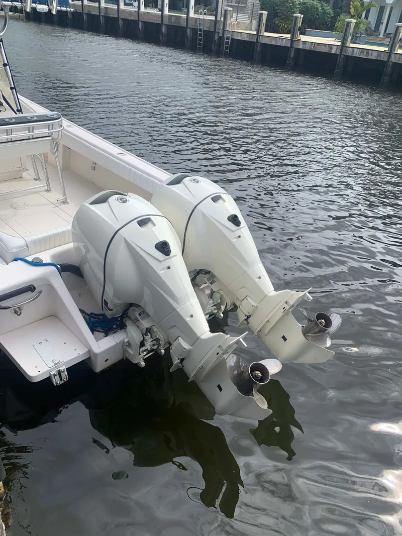 Slide: The Image of 1995 Intrepid 322 Cuddy with dual outboard motors docked on calm water. - 10