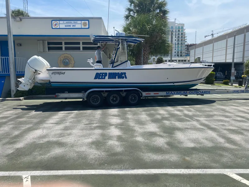 Slide: The Image of 1995 Intrepid 322 Cuddy boat on trailer, parked outdoors near buildings. - 2