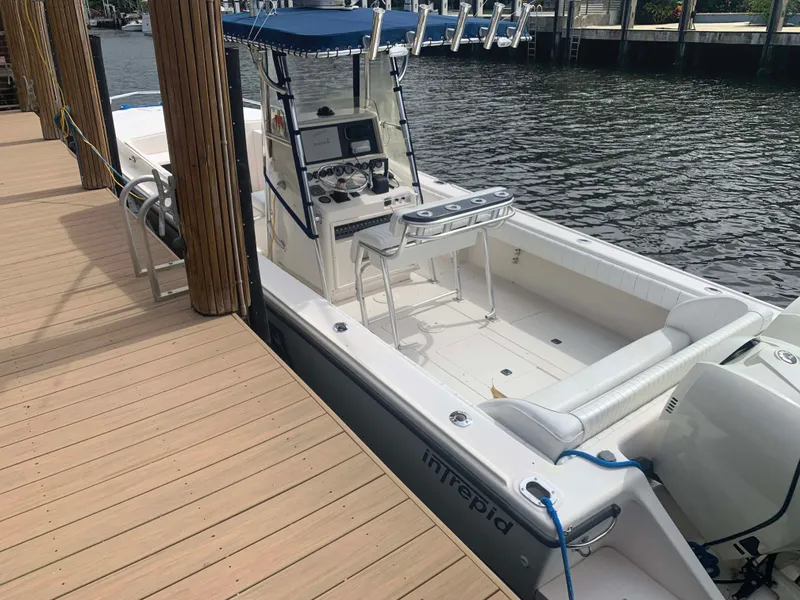 Slide: The Image of 1995 Intrepid 322 Cuddy boat docked by wooden pier, featuring sleek design and modern controls. - 6
