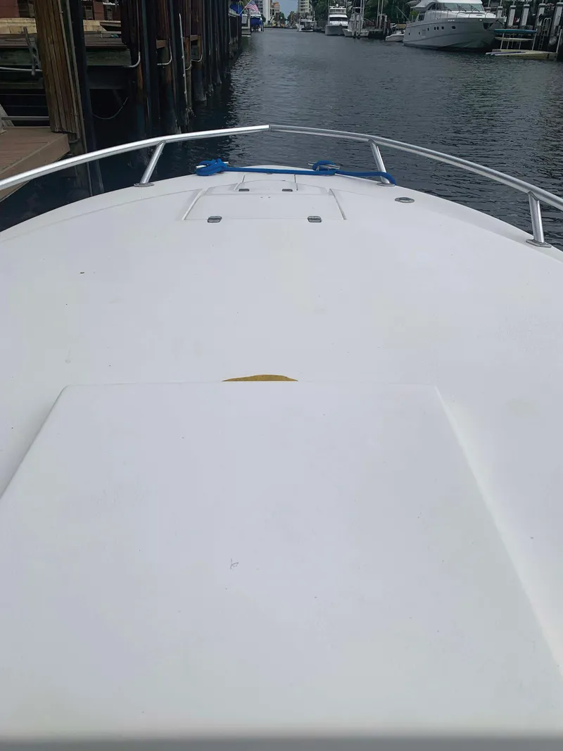 Slide: The Image of 1995 Intrepid 322 Cuddy boat on a calm waterway, docked near wooden piers. - 8