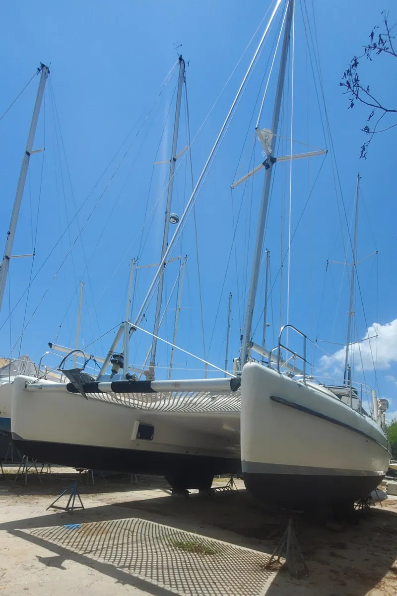 Slide: The Image of 1992 Fountaine Pajot Antigua 37 catamaran on dry dock under a clear blue sky. - 3