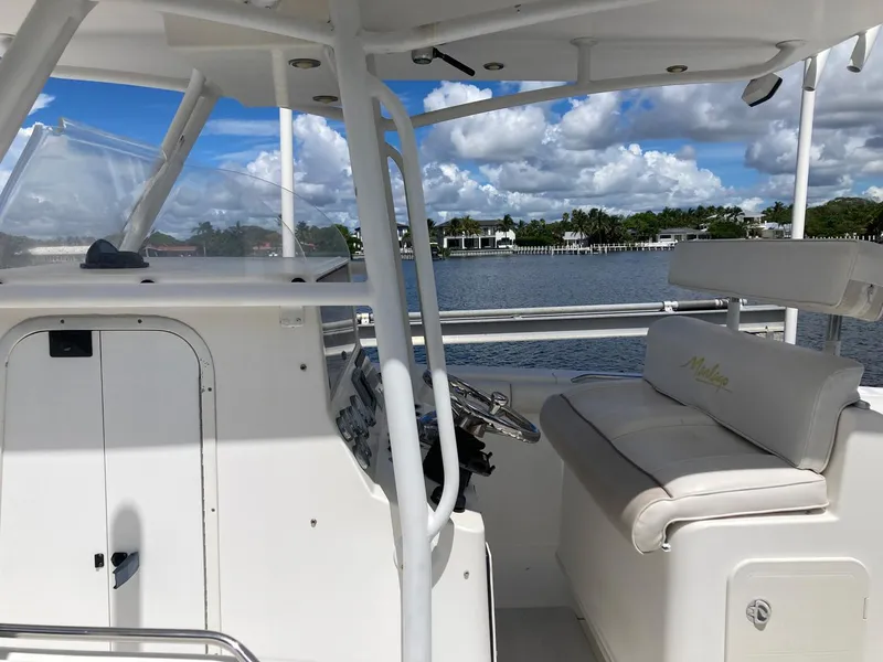 Slide: The Image of 2014 Marlago 35 boat interior with helm and seating, docked by a scenic waterfront. - 23