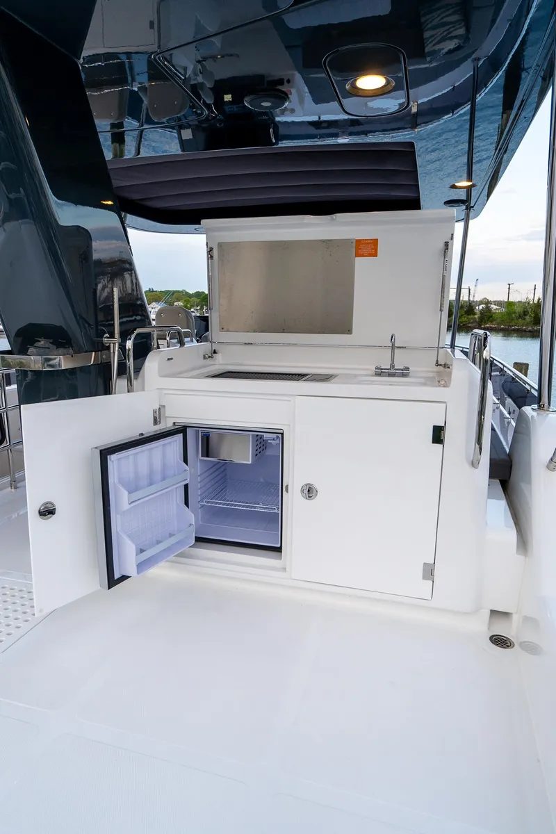 Slide: The Image of Outdoor kitchenette on 2024 Sirena 58 Flybridge yacht with open fridge and sink. - 21