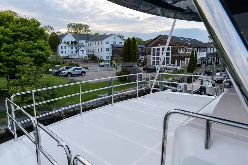 Slide: The Image of View from the Sirena 58 Flybridge yacht, 2024 model, docked near a scenic residential area. - 24