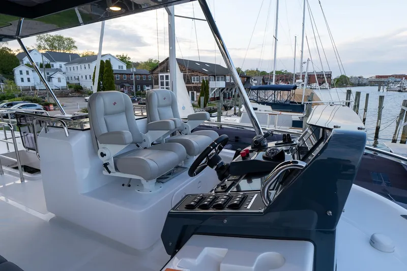 Slide: The Image of 2024 Sirena 58 Flybridge yacht helm station with dual captain chairs and waterfront view. - 29