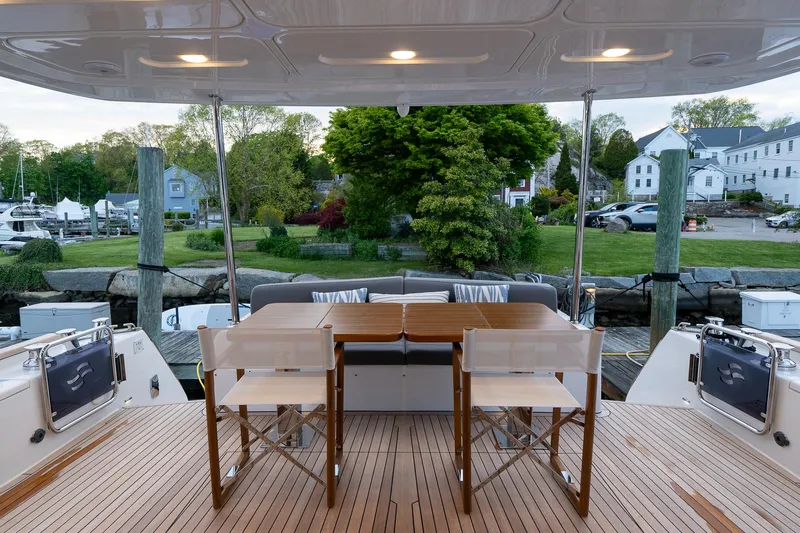 Slide: The Image of Outdoor dining area on the 2024 Sirena 58 Flybridge yacht, featuring a wooden table and chairs. - 9