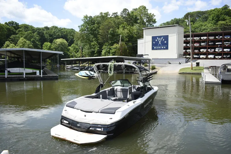 Slide: The Image of 2022 MasterCraft NXT22 boat docked at a marina with lush greenery. - 27