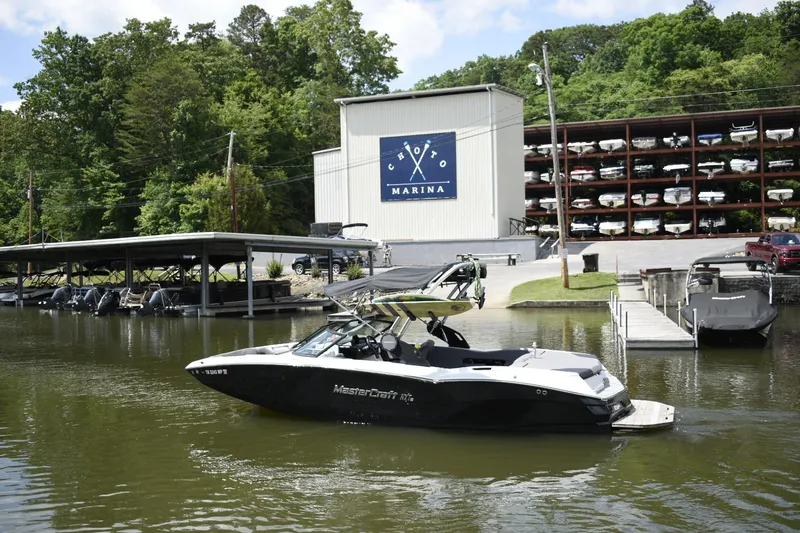 Slide: The Image of 2022 MasterCraft NXT22 boat docked at a marina with boat storage in the background. - 29