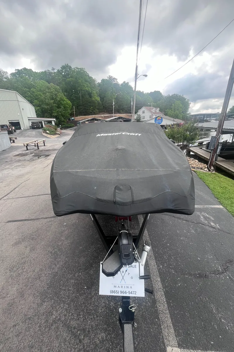 Slide: The Image of 2022 MasterCraft NXT22 boat covered, parked on a driveway under cloudy skies. - 37