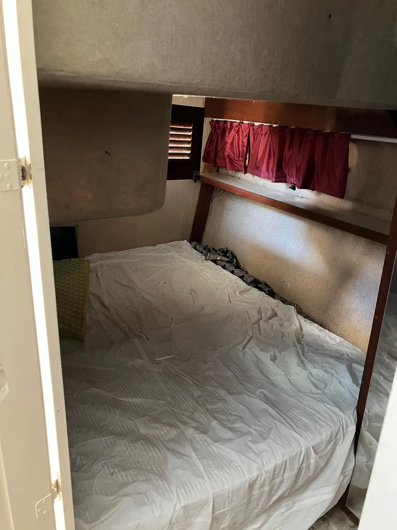 Slide: The Image of 1985 Cruisers Yachts 338 Chateau Vee cabin interior with bed and red curtains. - 17