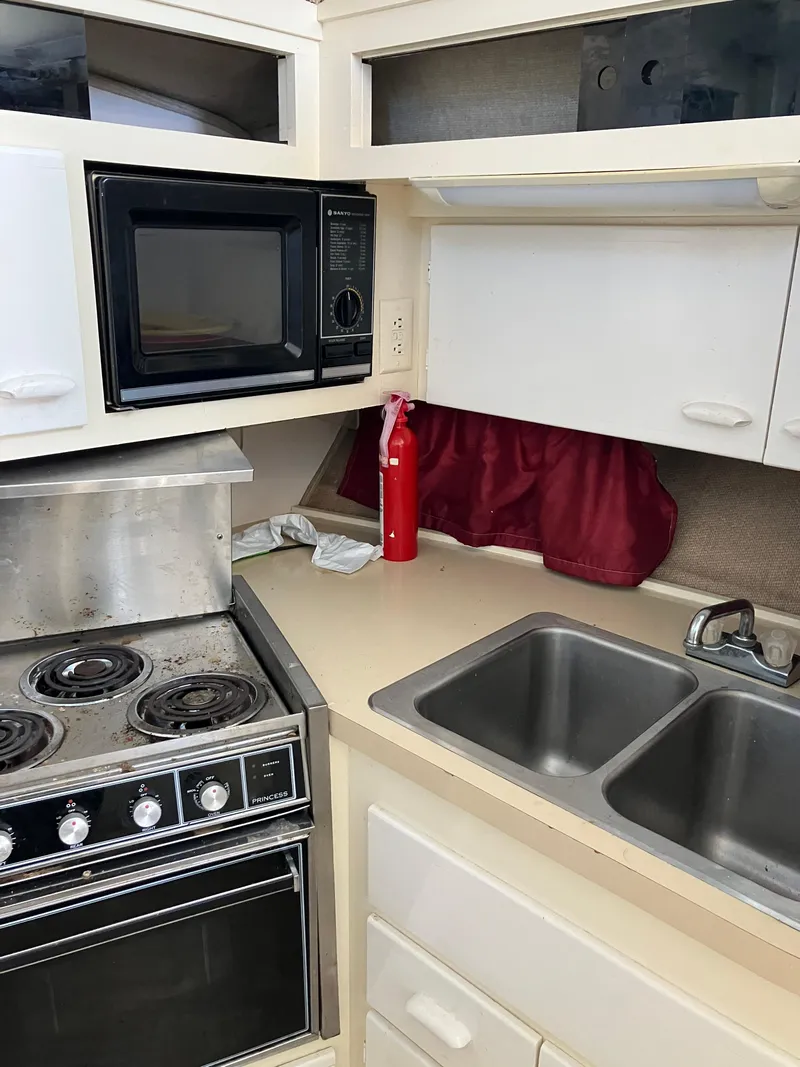 Slide: The Image of 1985 Cruisers Yachts 338 Chateau Vee kitchen with stove, microwave, sink, and fire extinguisher. - 18