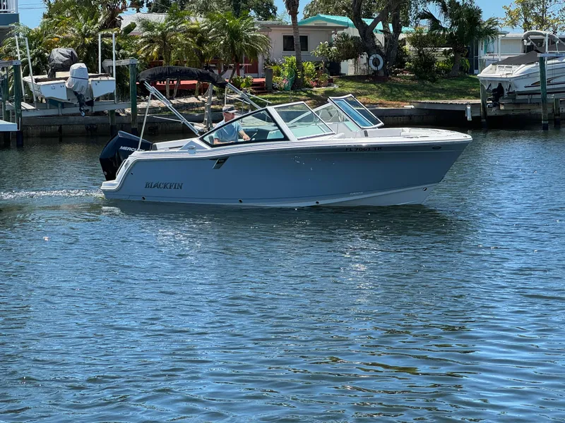 Slide: The Image of 2022 Blackfin 232 boat cruising on a sunny day in a marina. - 10