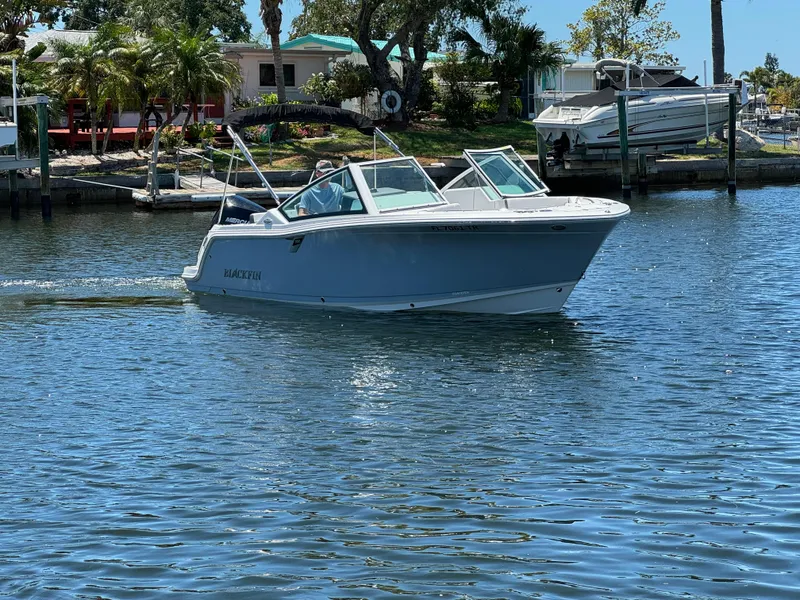 Slide: The Image of 2022 Blackfin 232 boat cruising on a sunny day near a dock. - 11