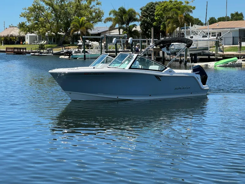Slide: The Image of 2022 Blackfin 232 boat cruising on a calm waterway near a residential area. - 6