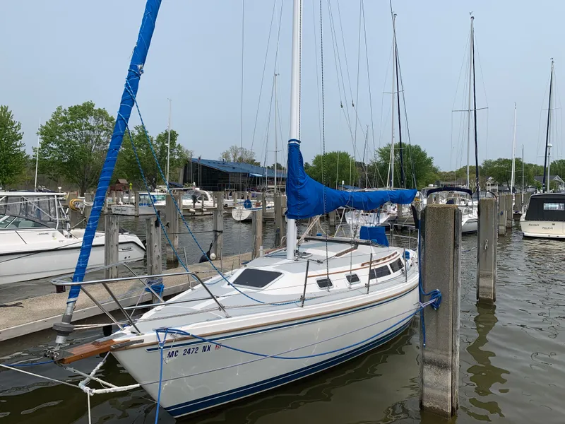 Slide: The Image of 1990 Catalina 30' Tall Rig sailboat docked in a marina, featuring blue sail covers. - 3