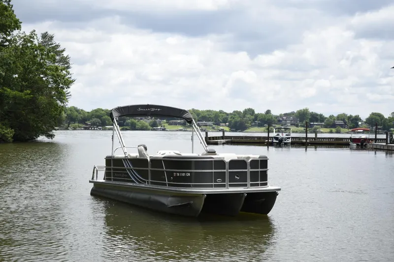 Slide: The Image of 2022 South Bay 224 RS LE pontoon boat on a serene lake. - 2