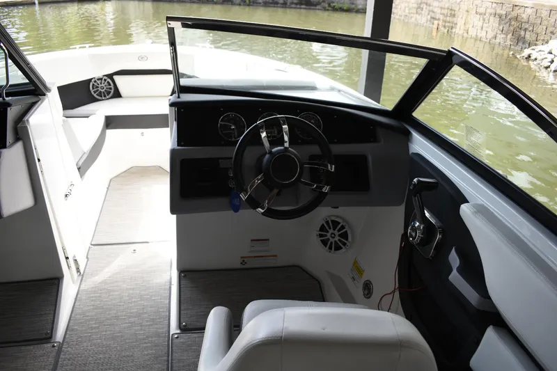 Slide: The Image of 2023 Cobalt CS22 boat interior with steering wheel and dashboard, docked by the water. - 11