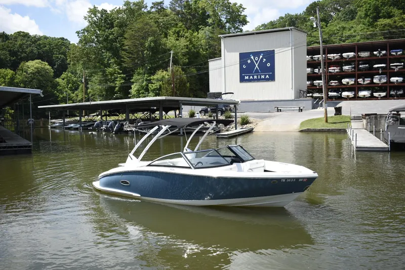 Slide: The Image of 2023 Cobalt CS22 boat at a marina with boat storage in the background. - 2