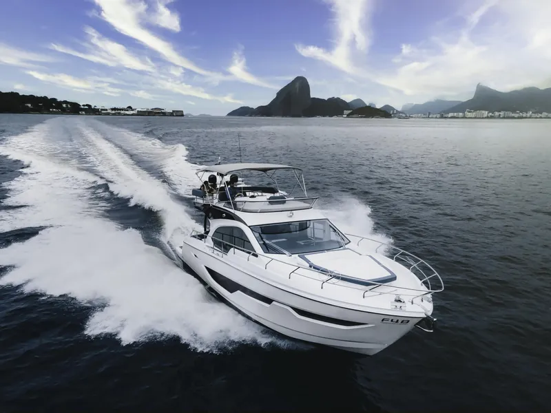 Slide: The Image of 2024 Sessa Marine Fly 48 yacht cruising on open water with scenic mountain backdrop. - 2
