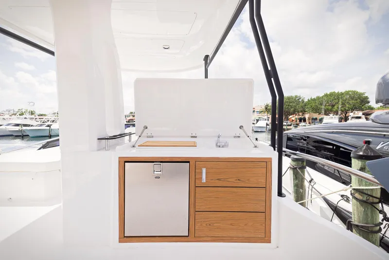 Slide: The Image of Outdoor kitchenette on 2024 Sessa Marine Fly 48 yacht, featuring wood cabinetry and stainless steel appliances. - 21