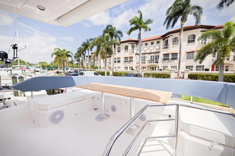 Slide: The Image of 2024 Sessa Marine Fly 48 yacht deck with seating, docked near palm trees and buildings. - 24