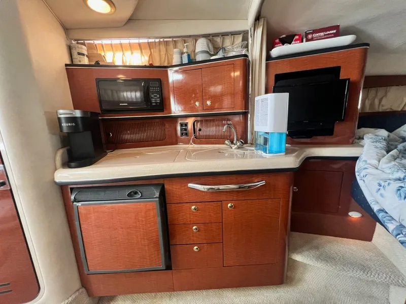 Slide: The Image of 2003 Sea Ray 300 Sundancer interior kitchen with microwave, sink, and compact fridge. - 21