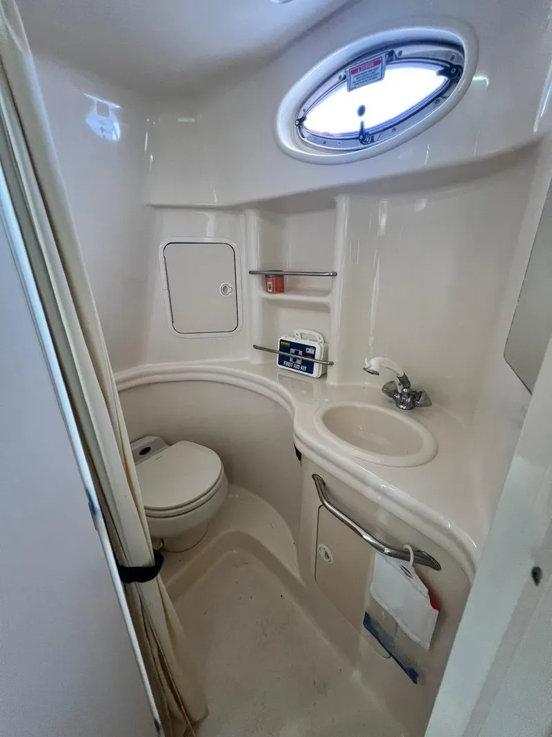 Slide: The Image of 2003 Sea Ray 300 Sundancer bathroom with sink, toilet, and porthole window. - 22