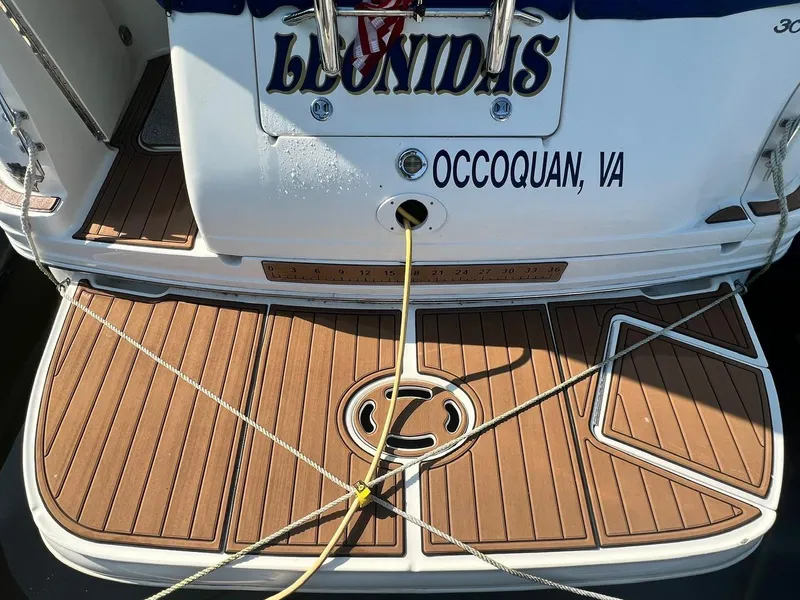 Slide: The Image of 2003 Sea Ray 300 Sundancer boat docked, featuring a wooden deck and mooring lines. - 3