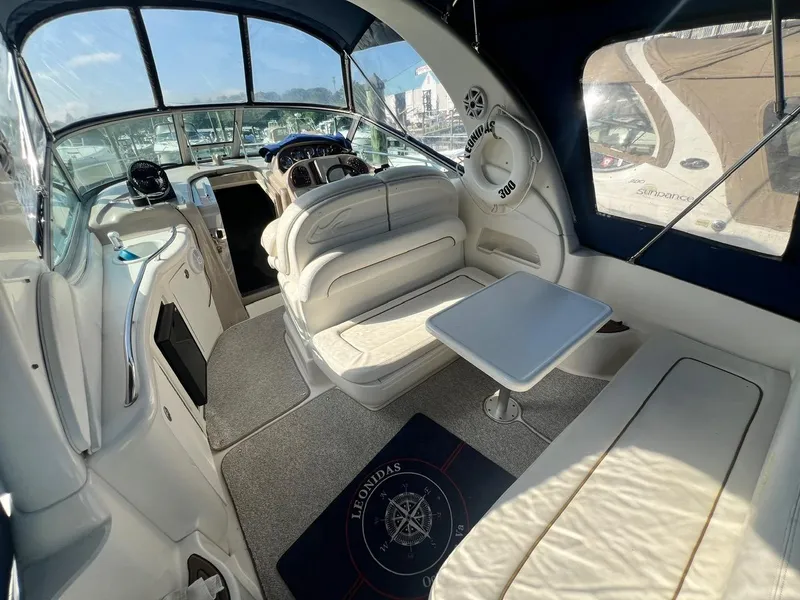 Slide: The Image of 2003 Sea Ray 300 Sundancer interior with seating, table, and helm, showcasing luxury boat design. - 4