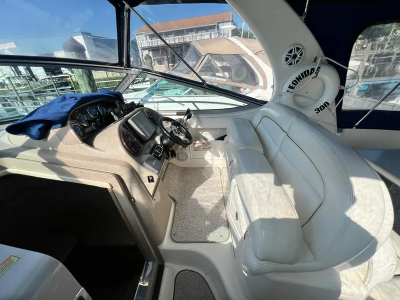 Slide: The Image of 2003 Sea Ray 300 Sundancer cockpit with steering wheel, dashboard, and white seating. - 7
