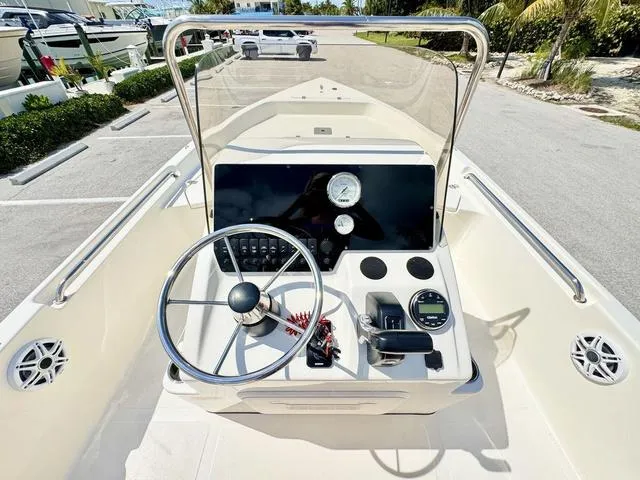 Slide: The Image of 2024 Bulls Bay 2000 boat dashboard with steering wheel and controls in a marina setting. - 9