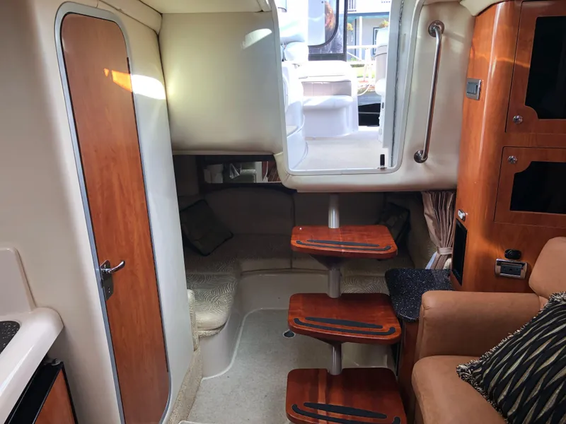 Slide: The Image of Interior of 2007 Four Winns 318 Vista boat, featuring wooden steps and cozy seating area. - 18