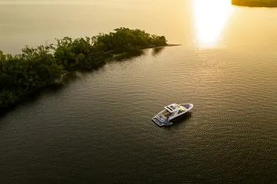 Slide: The Image of 2024 Sea Ray SLX 400 boat cruising at sunset near a lush island. - 71