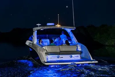 Slide: The Image of 2024 Sea Ray SLX 400 boat cruising at night with blue underwater lights. - 74
