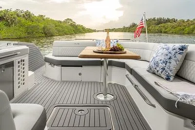 Slide: The Image of 2024 Sea Ray SLX 400 boat interior with seating, table, and scenic river view. - 80
