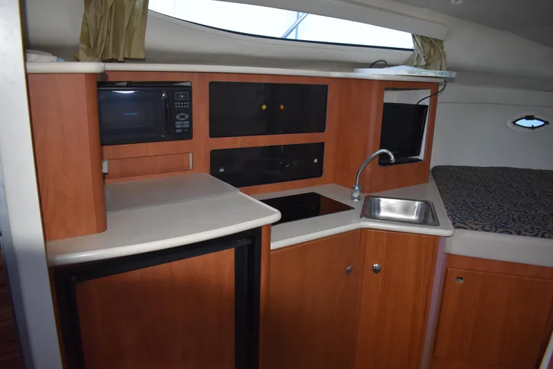 Slide: The Image of 2003 Bayliner 305 boat interior kitchen with microwave, sink, and mini-fridge. - 31