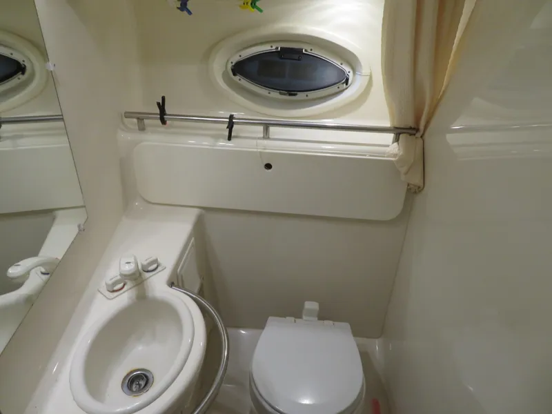 Slide: The Image of Compact bathroom in 2005 Maxum 3300 SE boat with sink, toilet, and porthole window. - 2