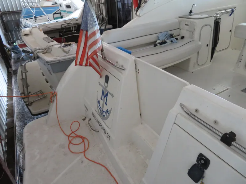 Slide: The Image of 2005 Maxum 3300 SE boat docked, featuring American flag and spacious seating area. - 26