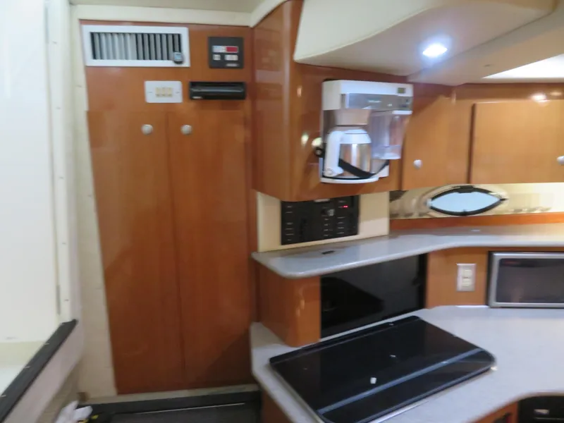 Slide: The Image of 2005 Maxum 3300 SE yacht interior with kitchenette, featuring wood cabinets and modern appliances. - 3