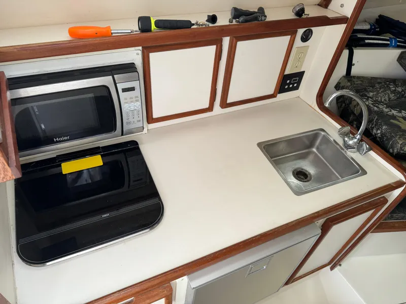 Slide: The Image of 1992 Blackfin 29 Express boat kitchen with microwave, sink, and storage cabinets. - 15
