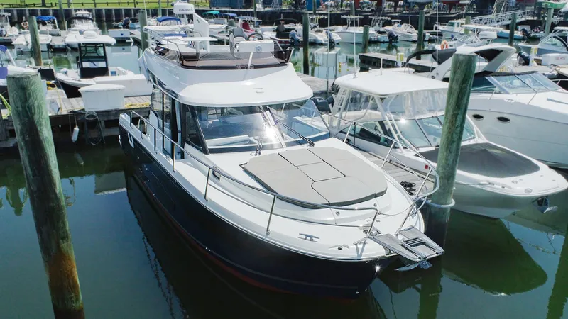 Slide: The Image of 2021 Jeanneau NC 1095 FLY docked in a marina, surrounded by other boats. - 1