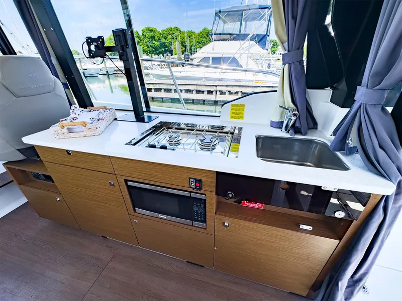 Slide: The Image of Modern kitchen area in a 2021 Jeanneau NC 1095 FLY boat with stove, sink, and microwave. - 13