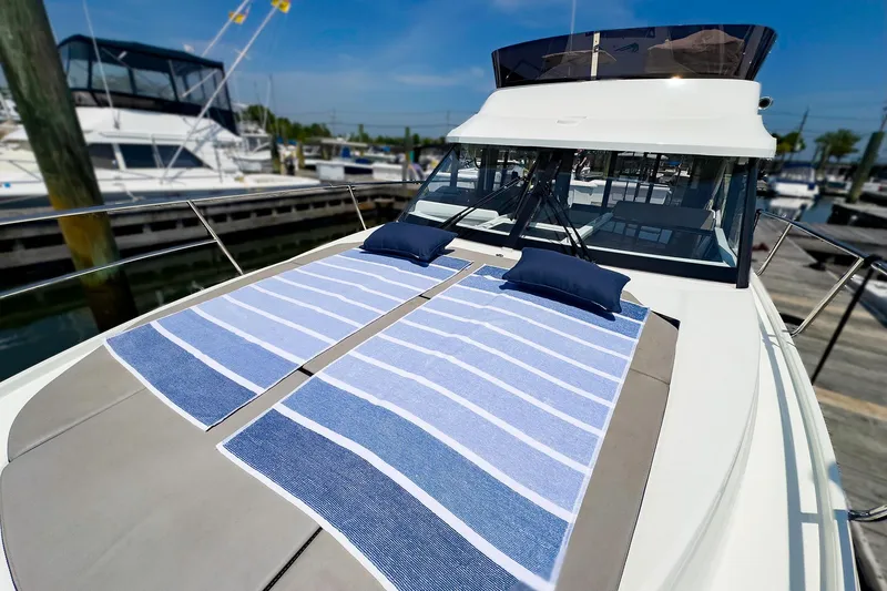 Slide: The Image of Jeanneau NC 1095 FLY 2021 model with sunbathing area and striped towels on deck. - 24