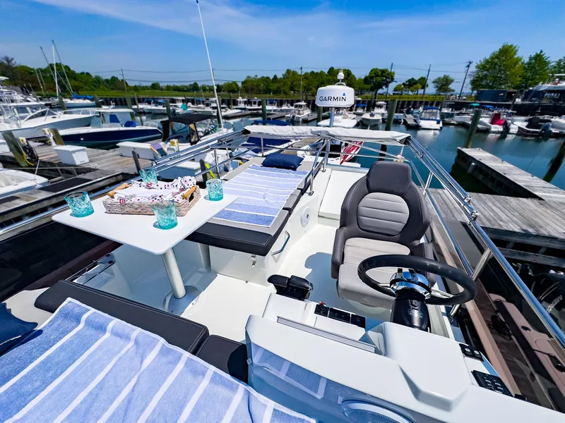 Slide: The Image of Flybridge of 2021 Jeanneau NC 1095 FLY yacht docked at marina, featuring seating and dining area. - 27
