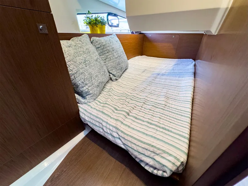 Slide: The Image of Cozy cabin bed in 2021 Jeanneau NC 1095 FLY yacht with striped bedding and decorative pillows. - 37